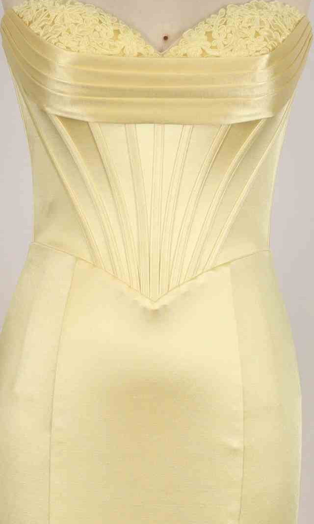 A close-up of the PromGirl Exclusive 250212, a pale yellow satin long prom dress with a strapless sweetheart neckline, pleated details, and floral lace at the neckline.